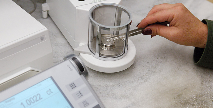 A grader in GIA’s laboratory utilizes a scale to determine the diamond’s carat weight.