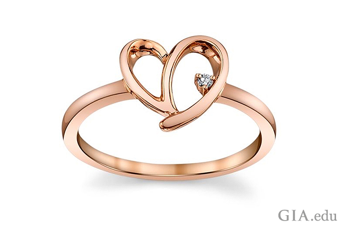 A 10K rose gold heart-motif ring is set with a 0.01 carat (ct) diamond.