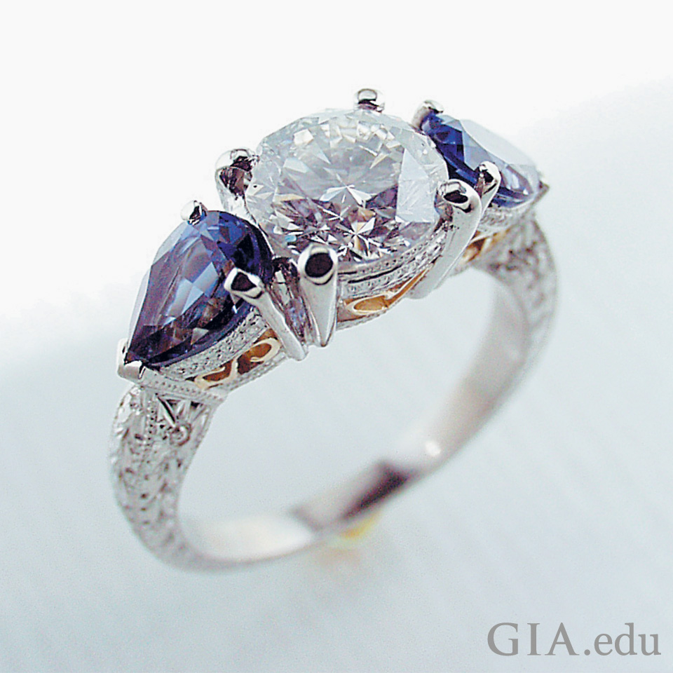 复古：这款镶有三颗宝石的华丽手工雕刻戒指采用了钻石主石和紫水晶辅石，在 18K 黄金和铂金戒面上环绕着珠镶米粒钻。
