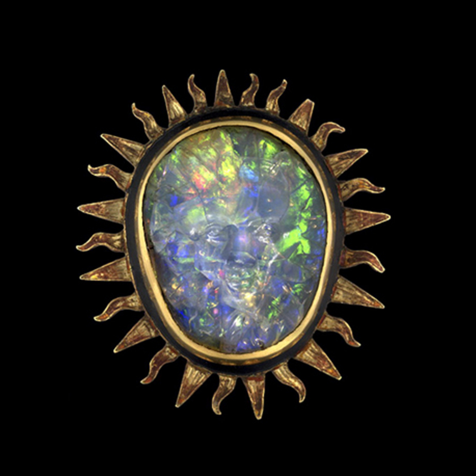 A vibrant opal set in a sunburst-shaped gold frame, showcasing a dazzling array of blue, green, and yellow hues.