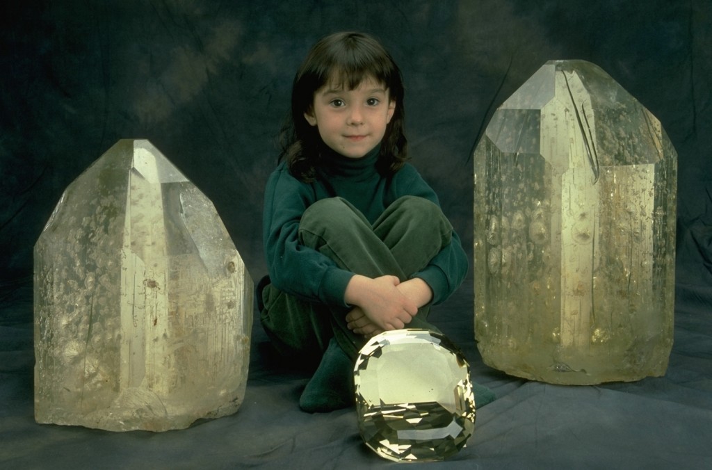 A child sitting between two large uncut gemstones.