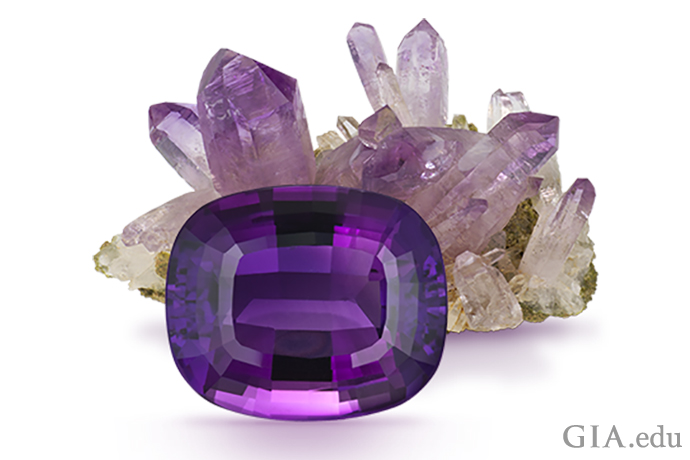 一颗22.62克拉 (ct) 的垫形切工紫水晶在其后方紫水晶原石的映衬下分外夺目。