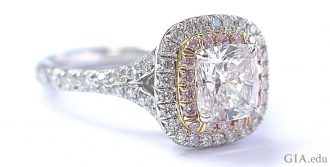 Cushion cut diamond and platinum engagement ring surrounded by a halo of melee and natural pink diamonds