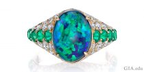 3.50 ct black opal, emerald and diamond ring. Set in 18k yellow gold.