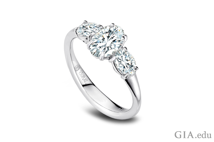 An oval cut diamond engagement ring featuring two diamond side stones.