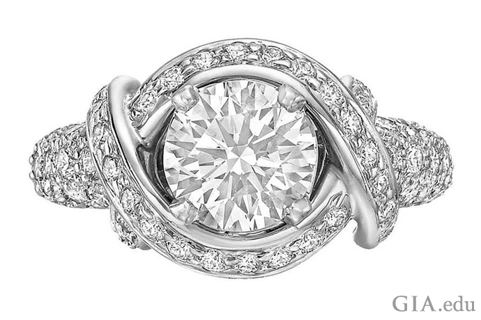 A 1.36 carat round brilliant cut diamond cradled by twisting bands of platinum studded with 0.96 carats of melee.