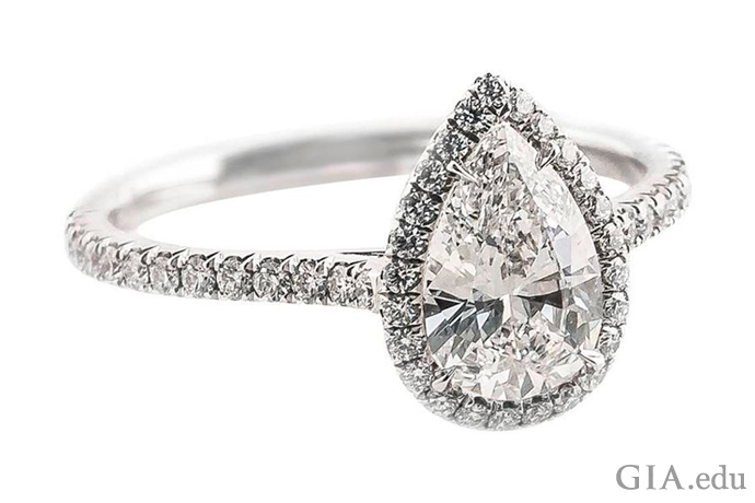 A 0.88 ct pear shaped diamond engagement ring accented with a halo of diamonds and melee in the shank.