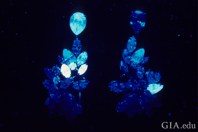 Diamond earrings viewed under a UV lamp showing different degrees of diamond fluorescence.