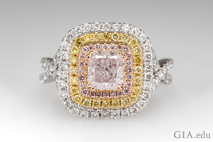 A fancy pink diamond engagement ring encircled by two halos of pink and yellow diamonds set in rose gold and yellow gold.