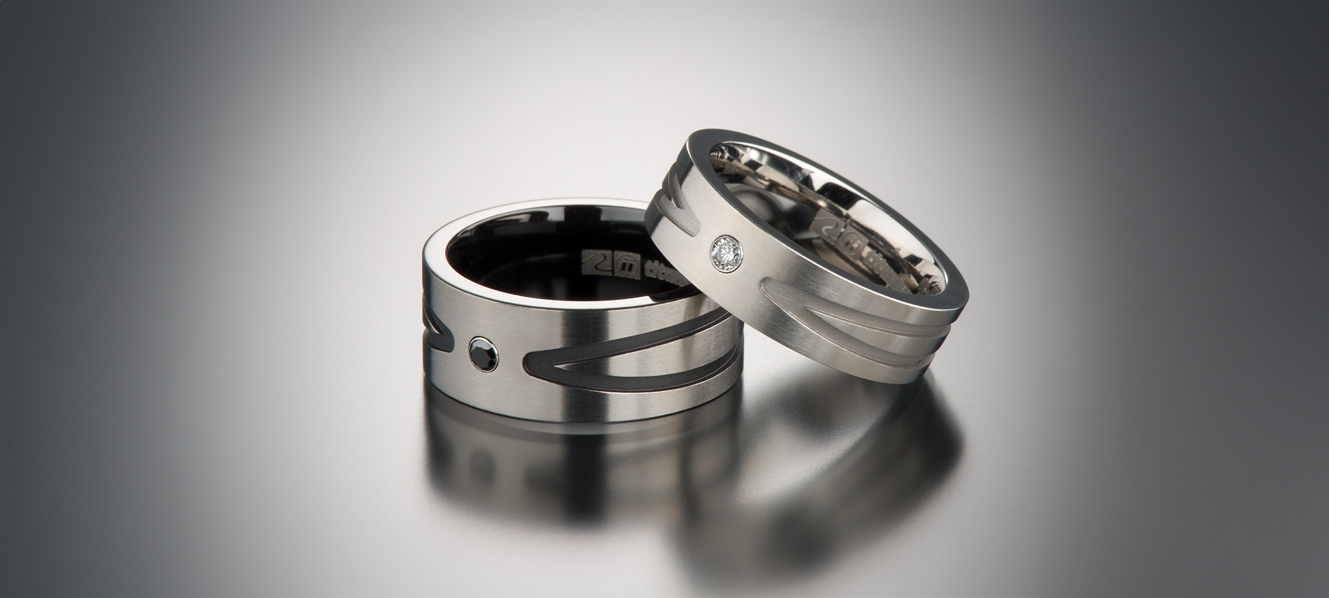Two titanium rings set with a black diamond and a colorless diamond