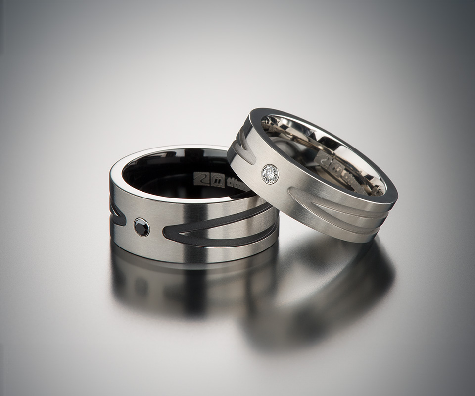 Two titanium rings set with a black diamond and a colorless diamond