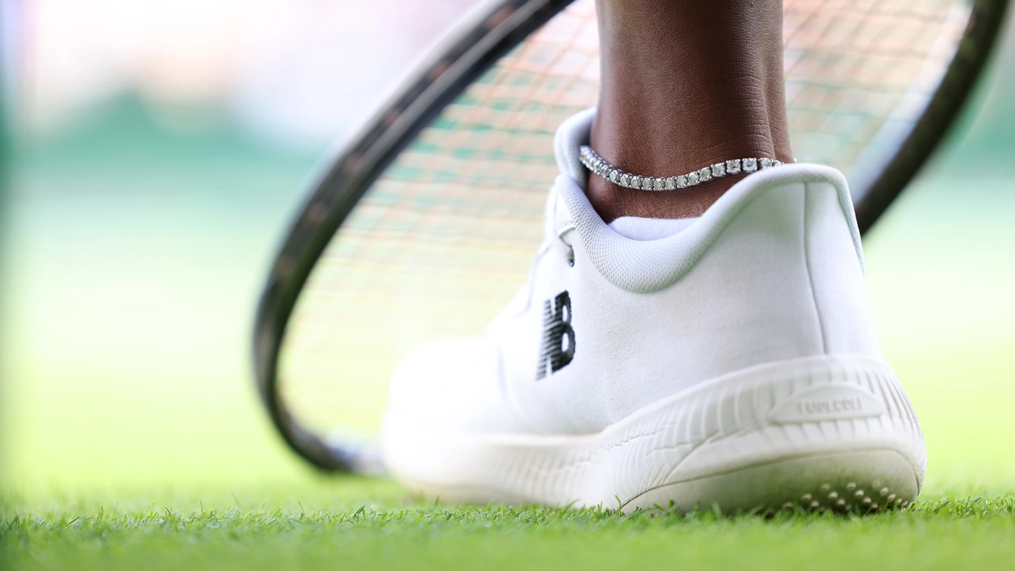 Close-up of tennis player Sloane Stephen’s diamond tennis anklet with her racket in the background.