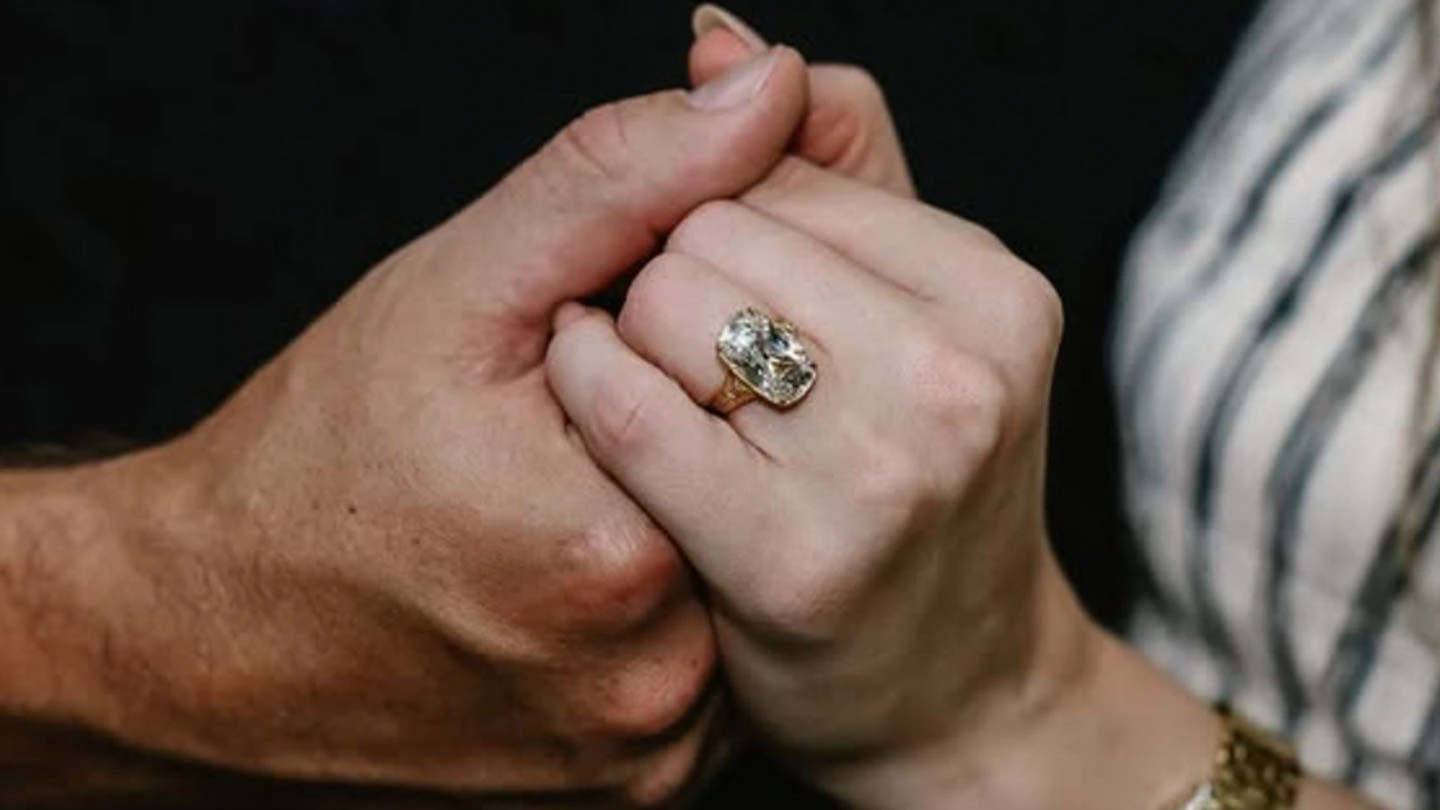Close up of Taylor Swift and Travis Kelce holding hands showing Swift's old mine cut diamond engagement ring