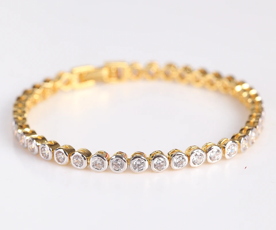 A white and yellow gold diamond tennis bracelet against a gray background