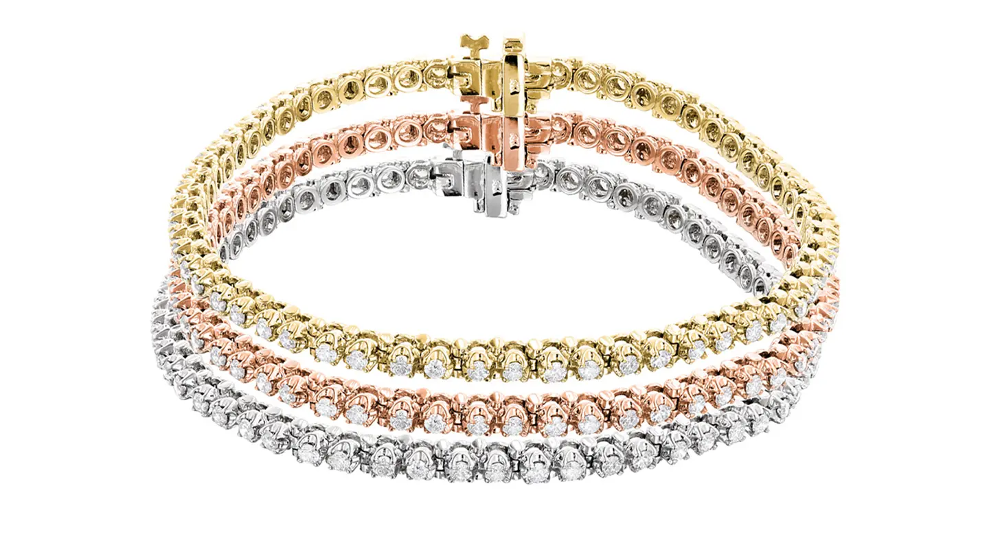 Three diamond tennis bracelets in white gold, rose gold and yellow gold stacked on top of each other.