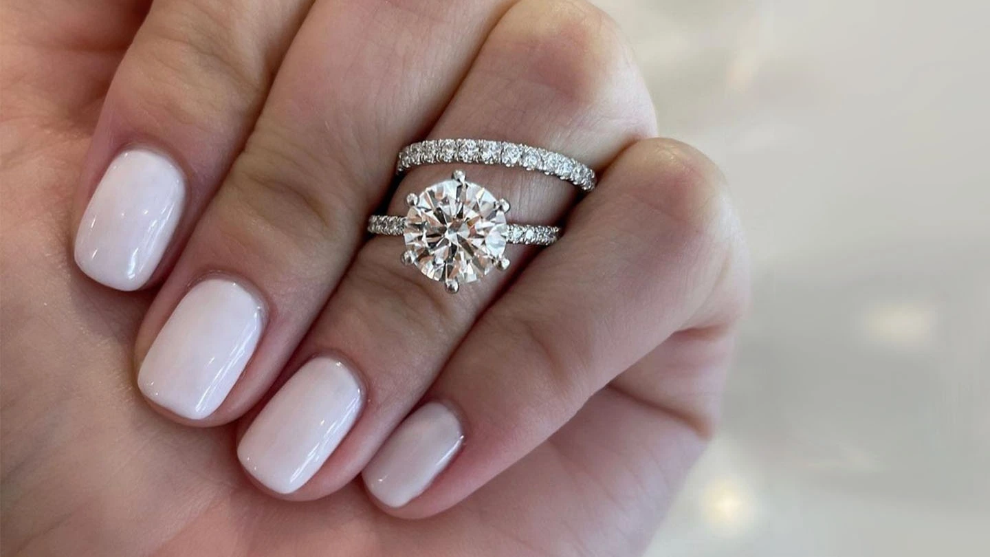 Woman’s hand with round brilliant diamond engagement ring and diamond melee wedding band