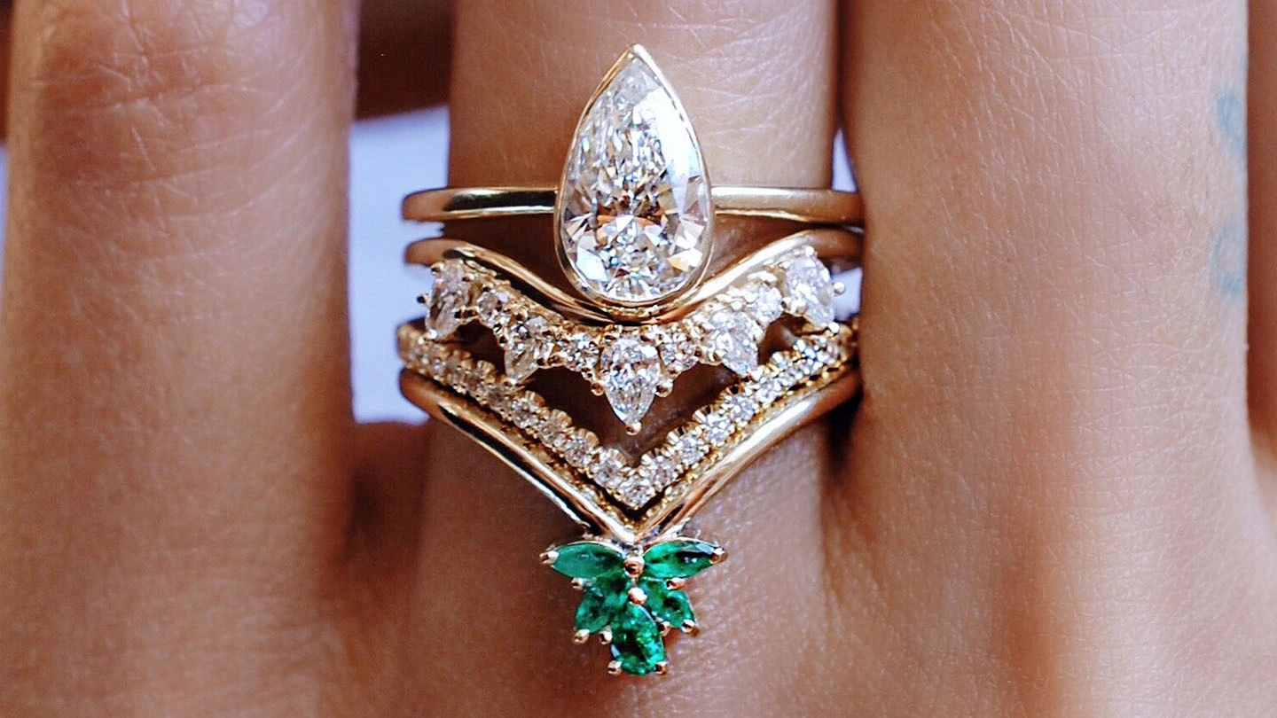 Woman’s hand with a diamond engagement ring and two stacked wedding bands.