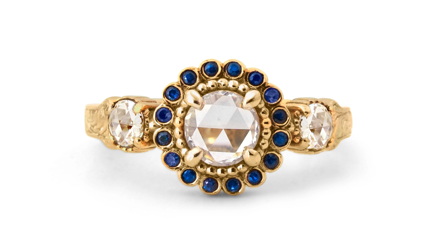 Three-stone rose cut diamond ring with sapphire halo.
