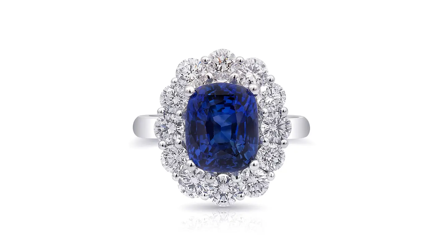 Blue sapphire ring with diamond halo on a white background