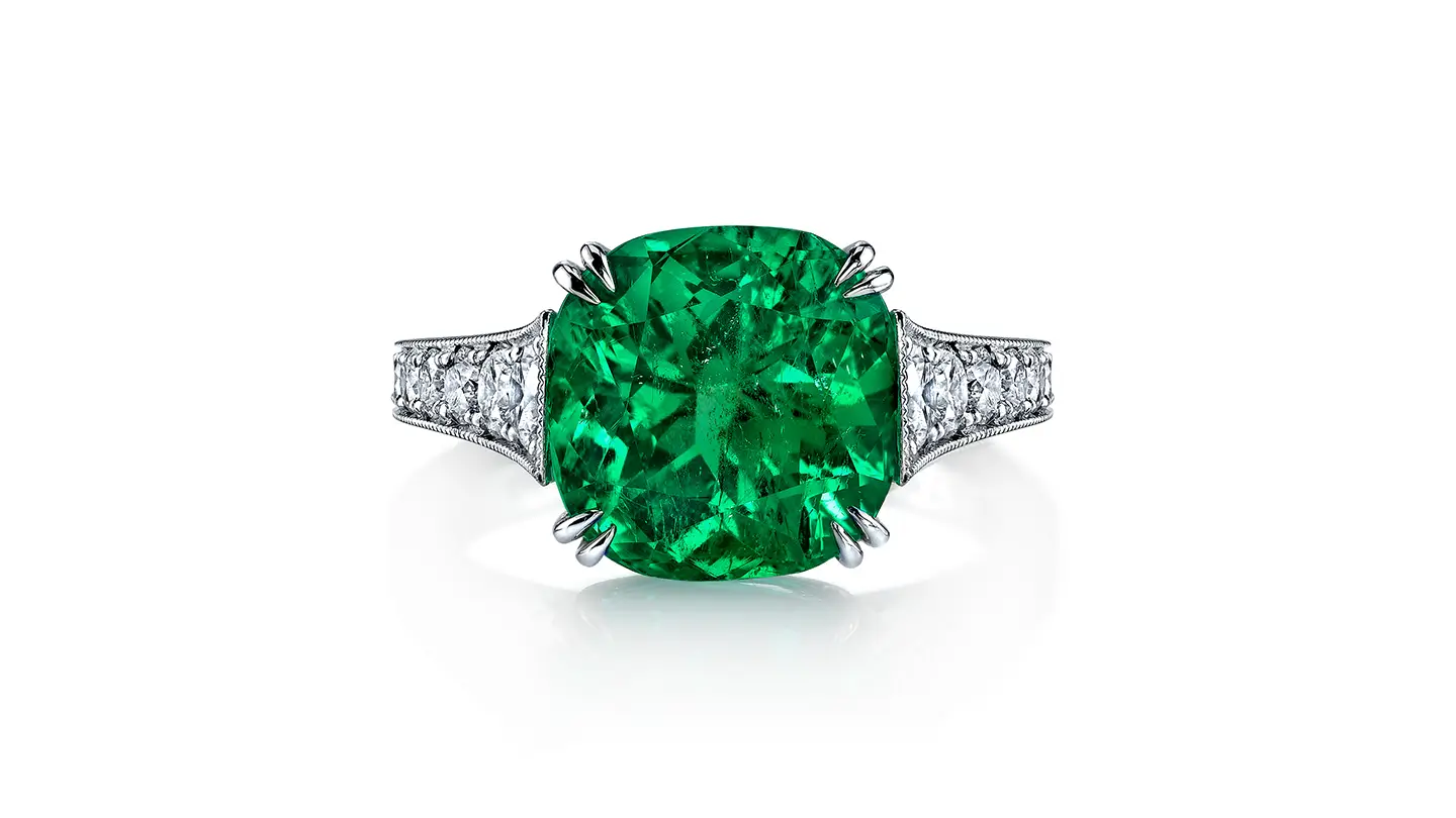 Cushion-cut emerald ring with diamond pavé, platinum band on white background