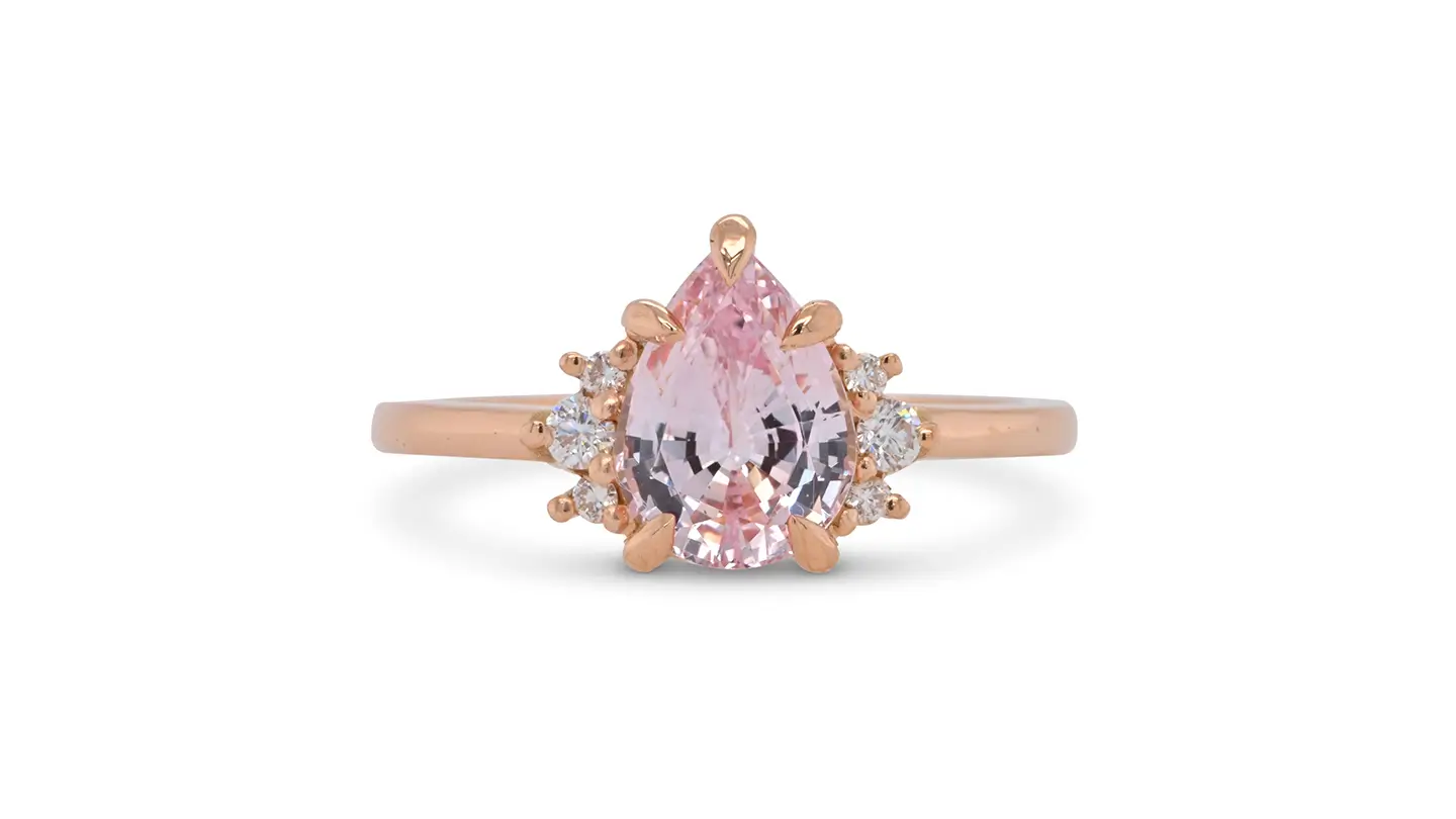 Pear-shaped morganite rose gold ring with diamond accents on white background