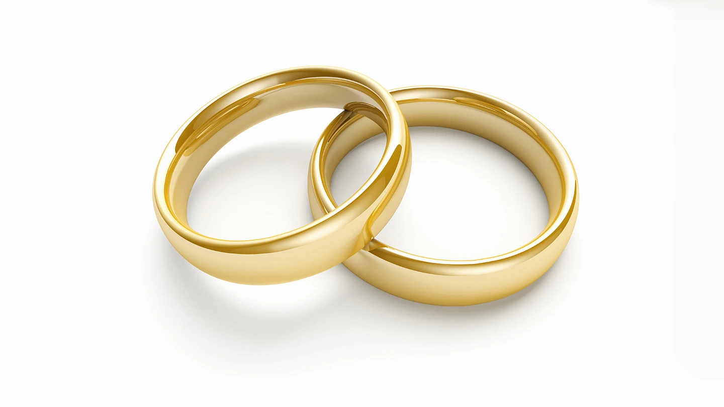 A matching set of traditional gold band engagement rings against white background