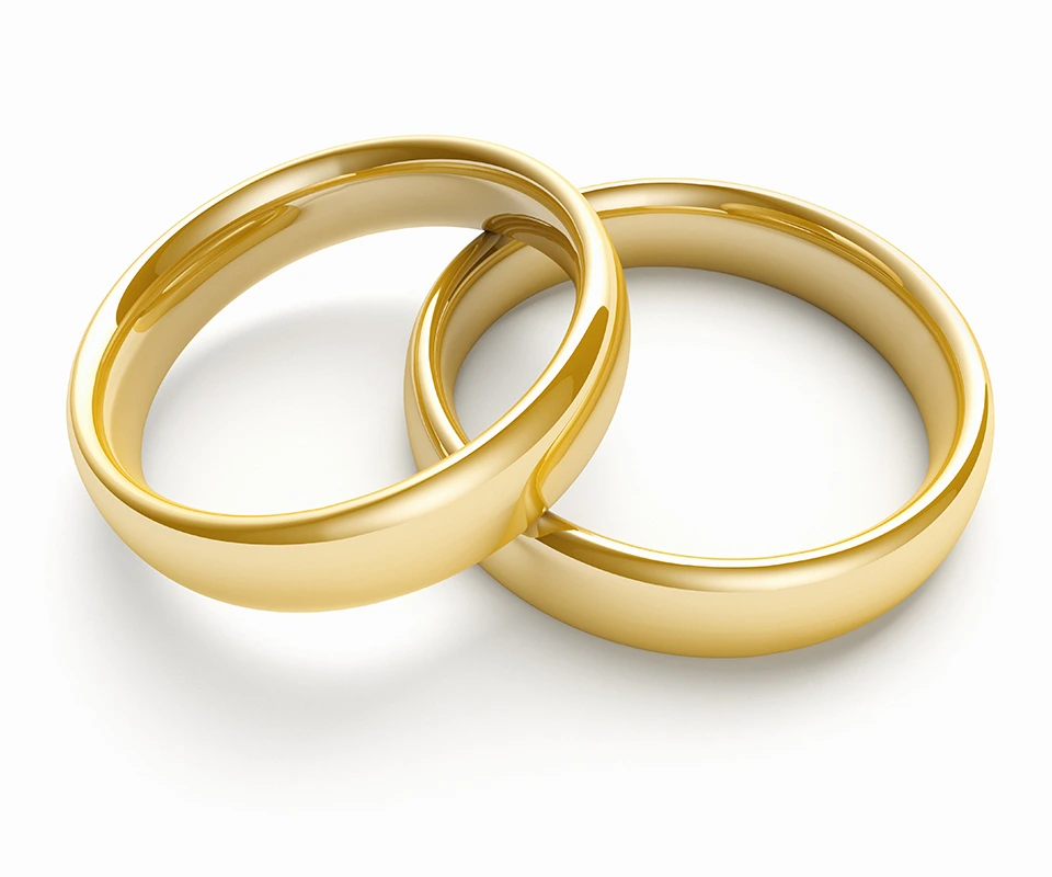 A matching set of traditional gold band engagement rings against white background