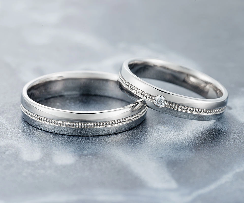 Matching white gold wedding bands with milgrain on a gray table