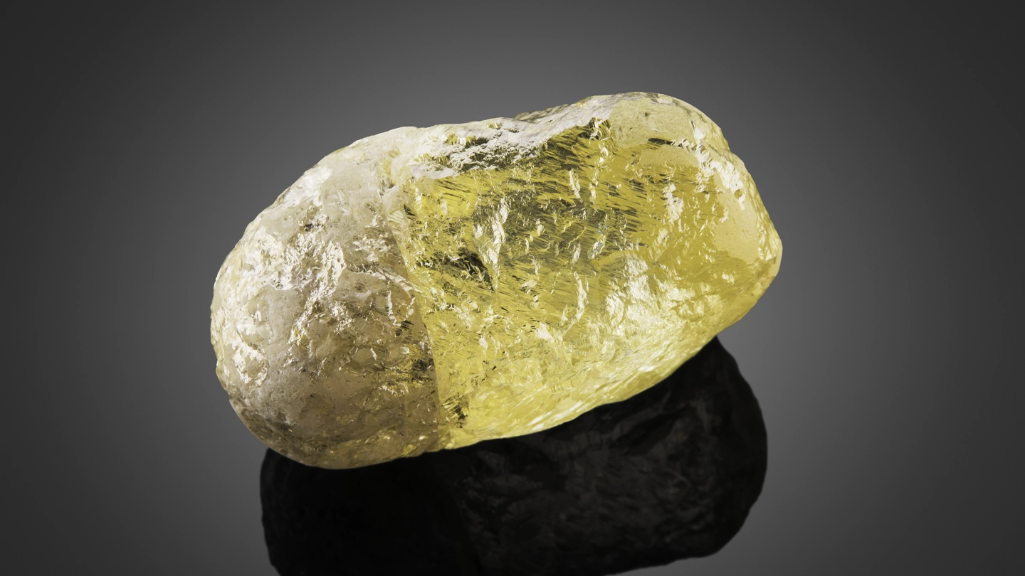 Large yellow diamond crystal rough from Canada on a dark gray background