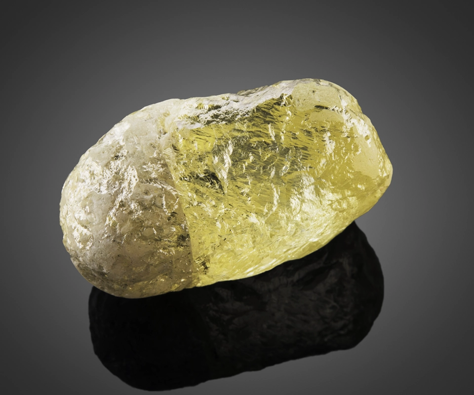 Large yellow diamond crystal rough from Canada on a dark gray background