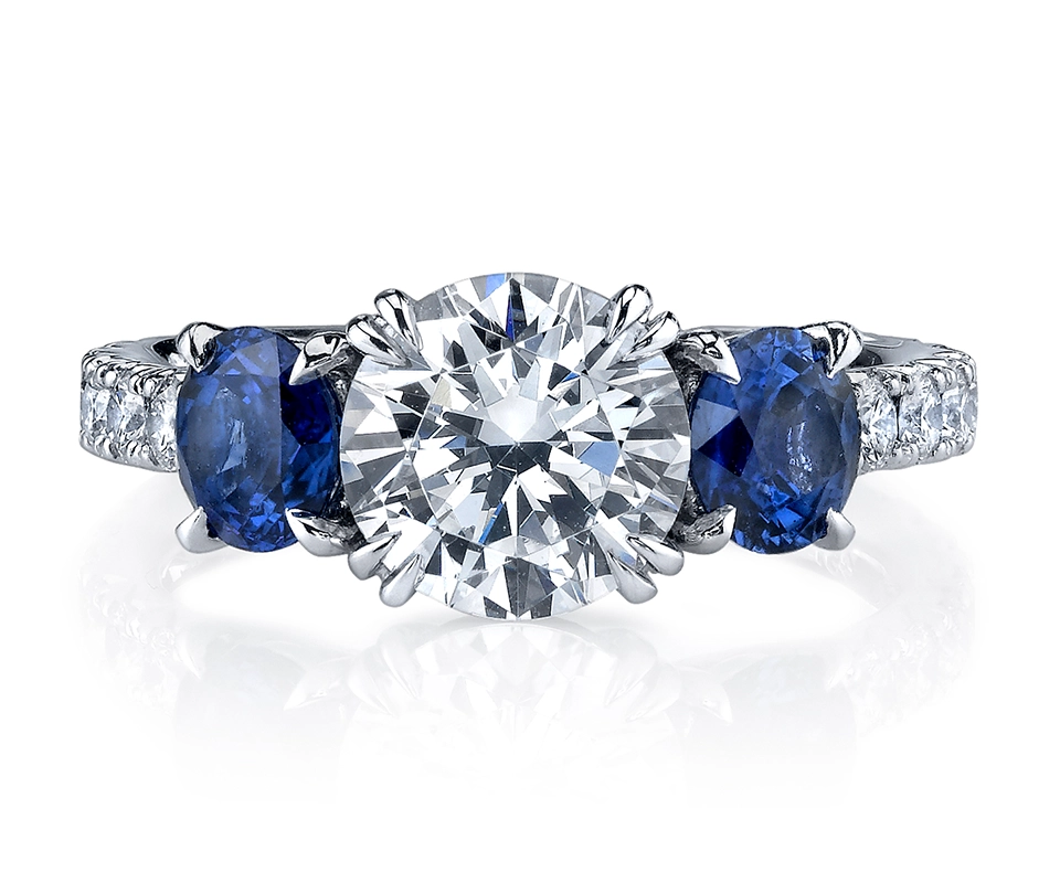 Three-stone ring with round diamond center and blue sapphire side stones