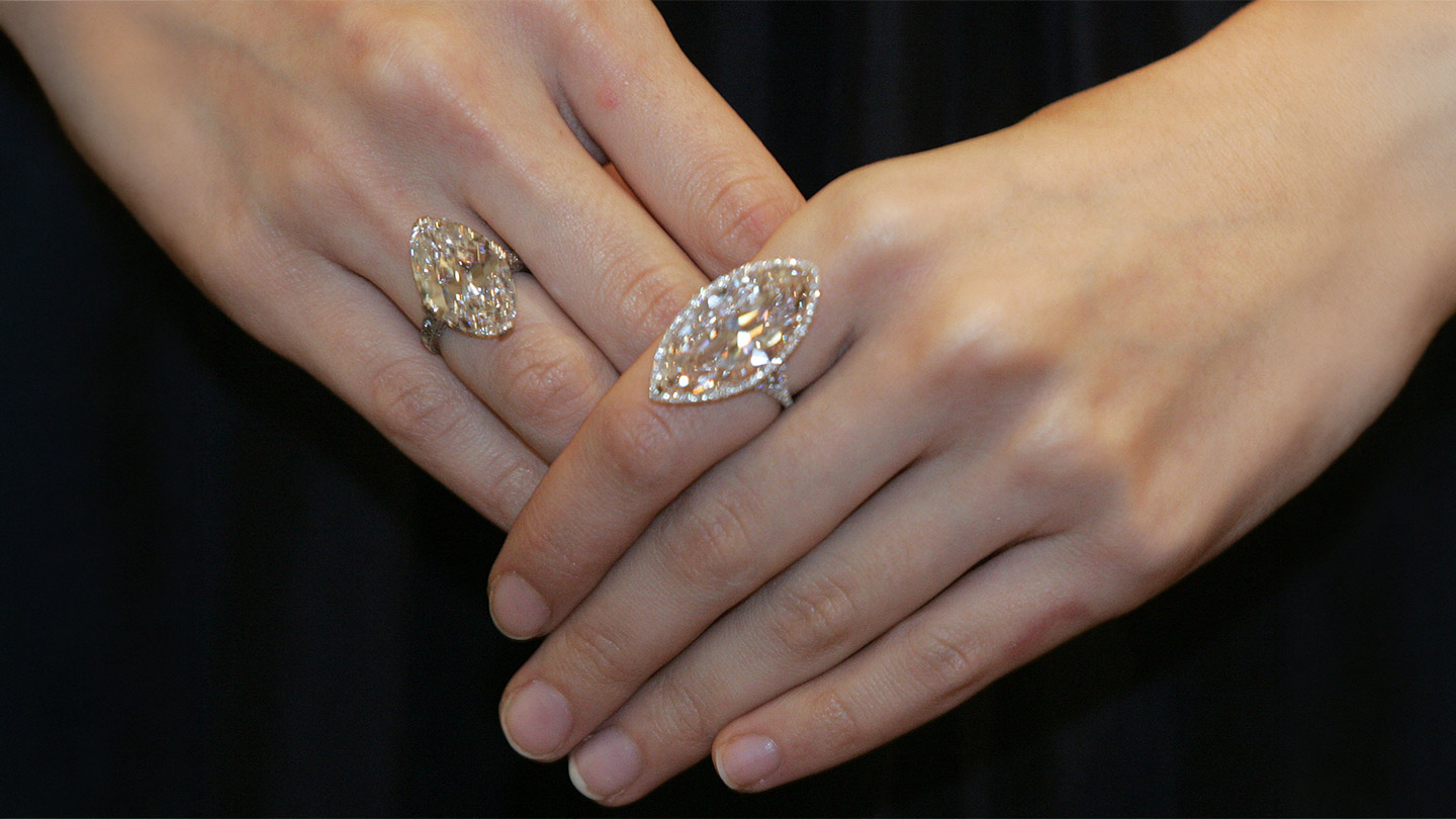 Two engagement rings with large warm-colored marquise-cut diamonds, one set as a solitaire and one with a diamond halo.