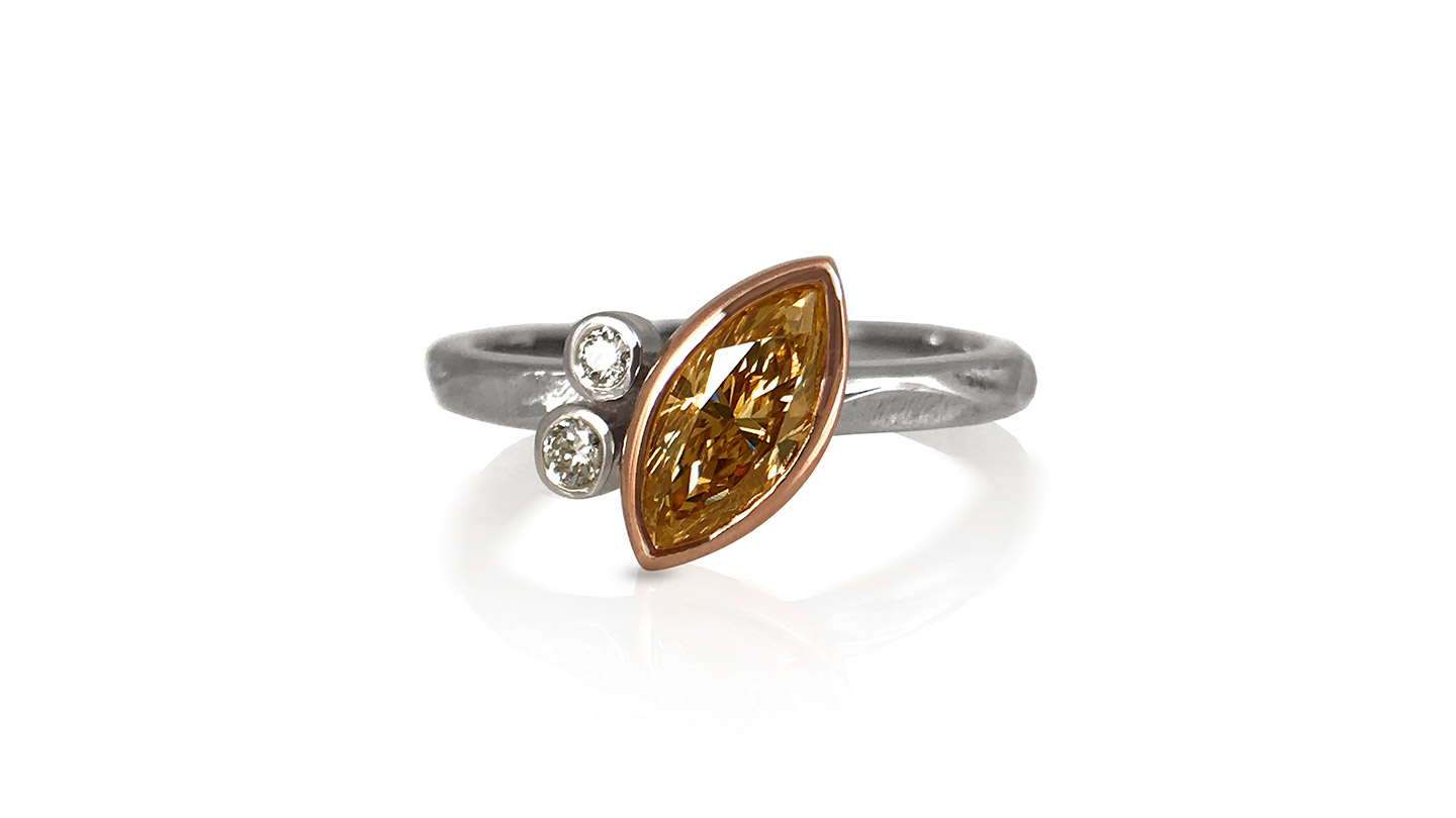 Marquise-cut brown diamond bezel set ring with two round diamond accents.