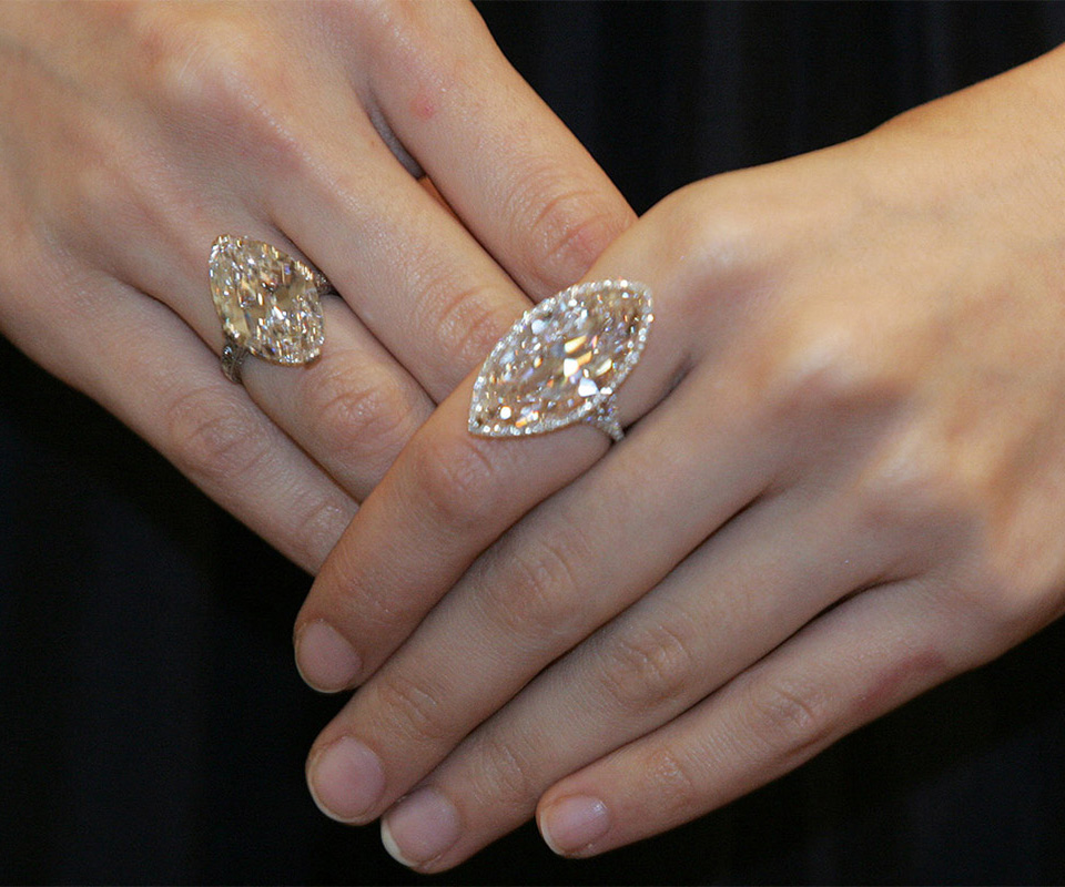 Two engagement rings with large warm-colored marquise-cut diamonds, one set as a solitaire and one with a diamond halo.