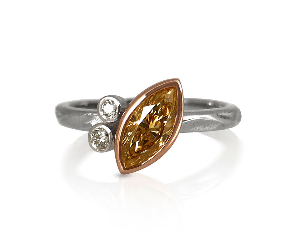 Marquise-cut brown diamond bezel set ring with two round diamond accents.